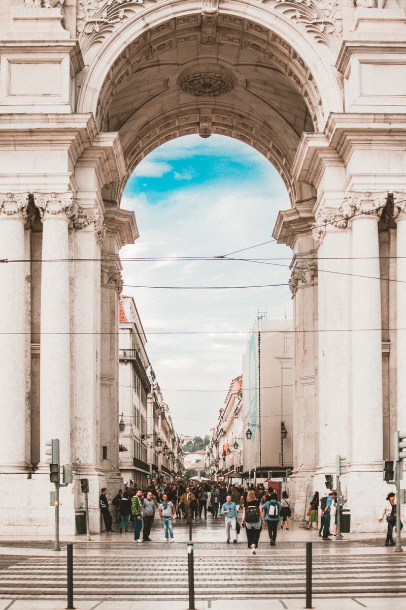 People Walking Under White Concrete Architecture